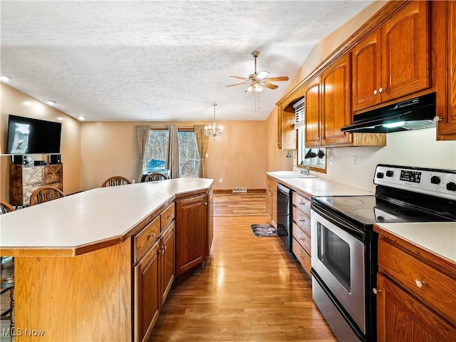 kitchen with under cabinet range hood, stainless steel electric range oven, light countertops, and lofted ceiling