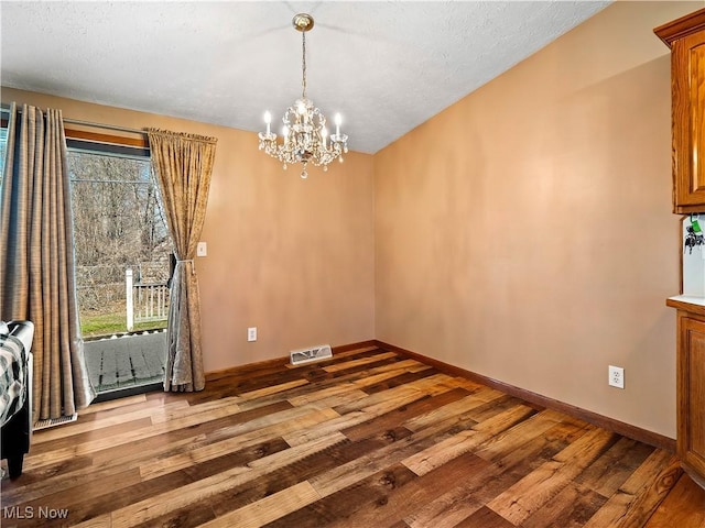 unfurnished dining area with visible vents, plenty of natural light, baseboards, and wood finished floors