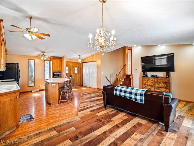 living area with visible vents, lofted ceiling, light wood-style floors, baseboards, and stairs