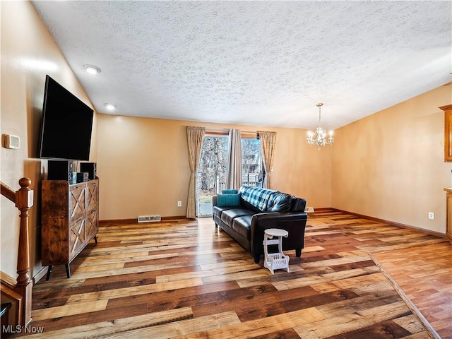 living area with an inviting chandelier, light wood-style floors, baseboards, and vaulted ceiling