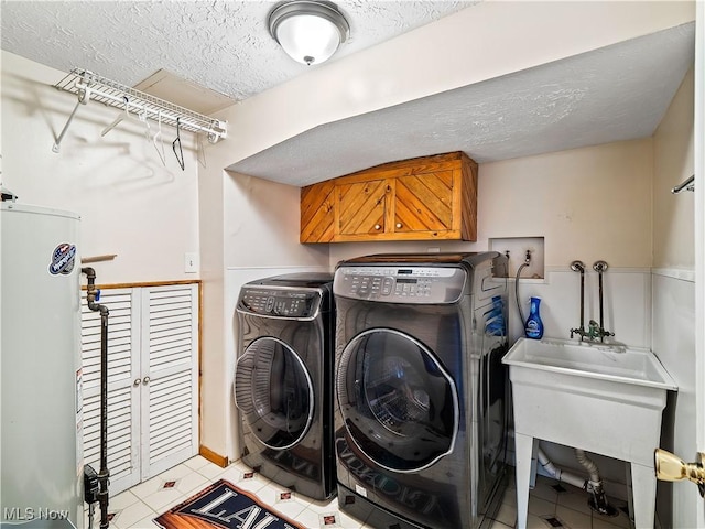 washroom with cabinet space, separate washer and dryer, water heater, tile patterned flooring, and a textured ceiling