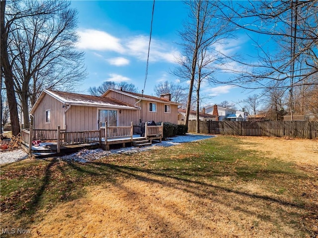 back of property with a yard, a deck, a chimney, and fence