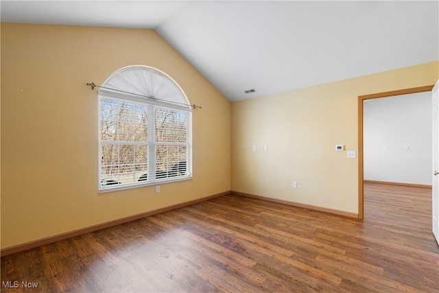 empty room featuring vaulted ceiling, wood finished floors, visible vents, and baseboards