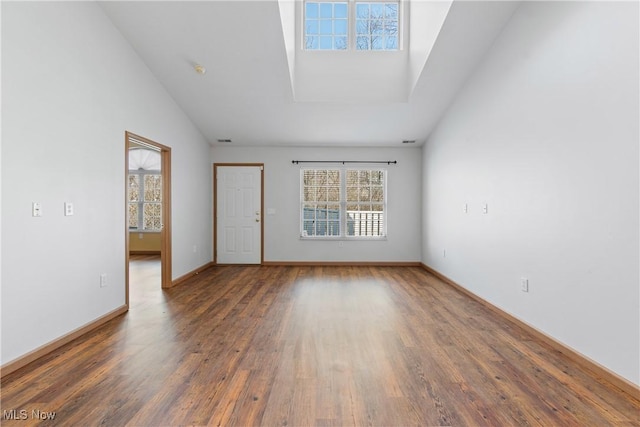 unfurnished room with visible vents, high vaulted ceiling, baseboards, and wood finished floors