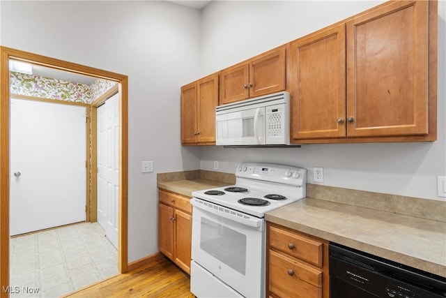 kitchen featuring brown cabinets, white appliances, light countertops, and light floors