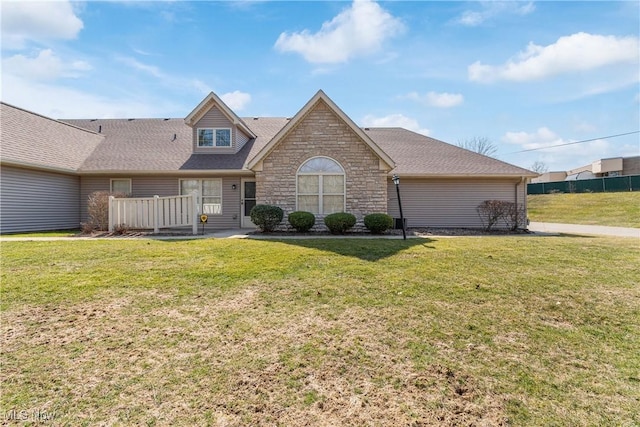 view of front of home featuring stone siding, roof with shingles, and a front lawn