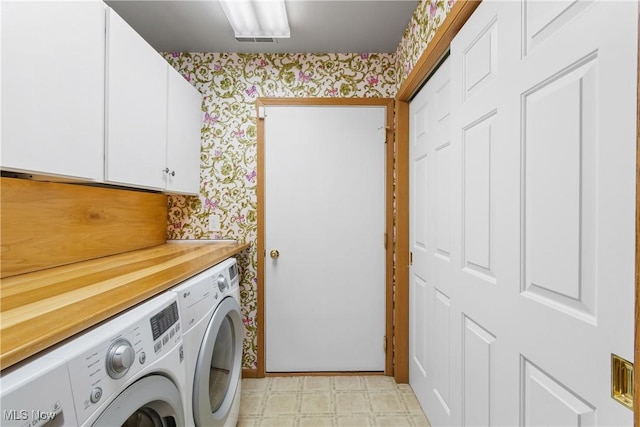 washroom with cabinet space, washer and dryer, wallpapered walls, and light floors