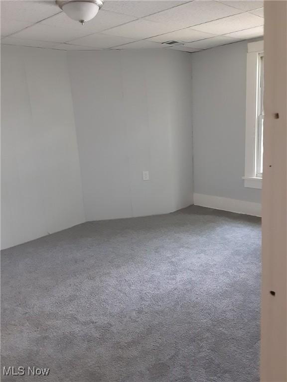 unfurnished room featuring carpet and a drop ceiling