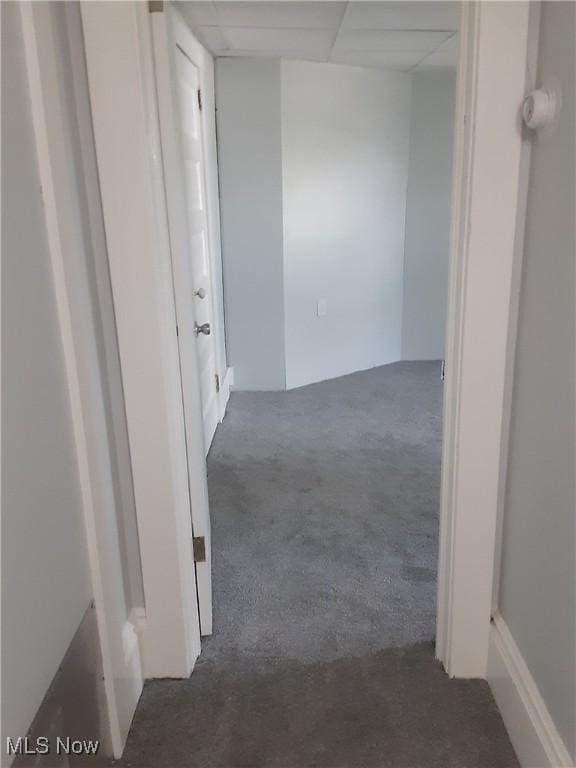 hallway with a paneled ceiling and carpet