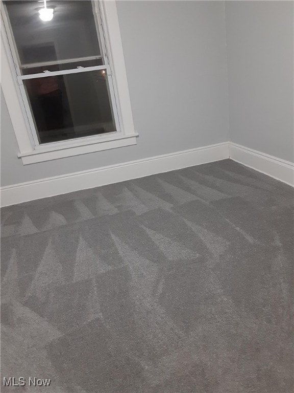 carpeted empty room featuring baseboards