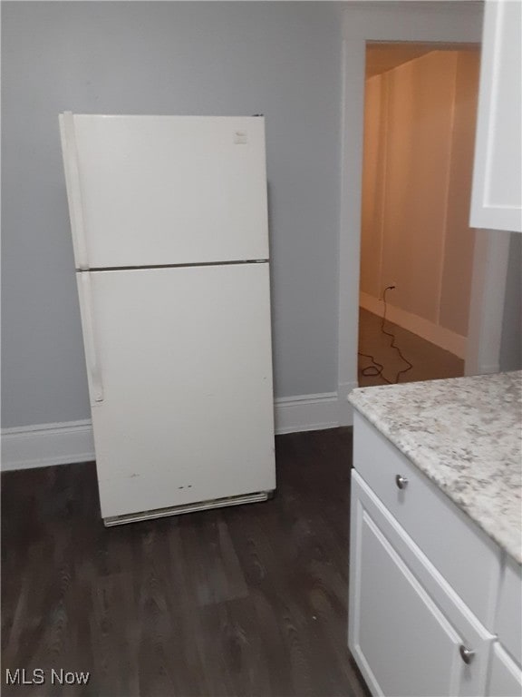 kitchen featuring baseboards, dark wood-type flooring, white cabinets, and freestanding refrigerator