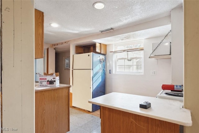 kitchen featuring visible vents, light floors, light countertops, white appliances, and a textured ceiling