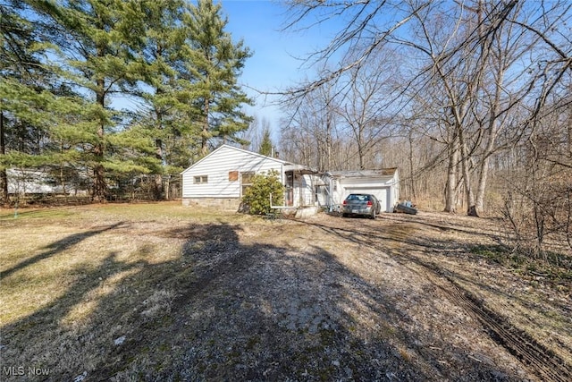 view of yard featuring an attached garage and dirt driveway