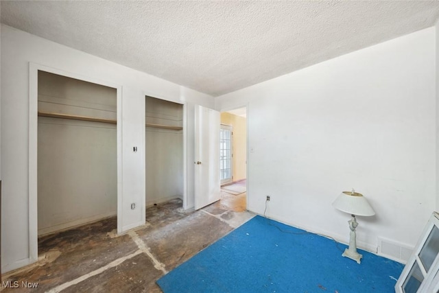 bedroom featuring visible vents, multiple closets, and a textured ceiling