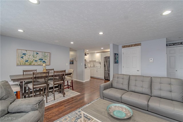 living room featuring dark wood-style floors, recessed lighting, a textured ceiling, and baseboards