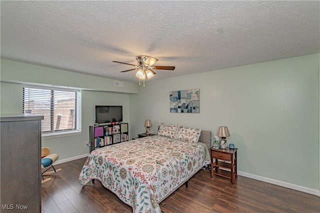 bedroom featuring wood finished floors, visible vents, baseboards, ceiling fan, and a textured ceiling