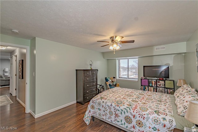 bedroom with visible vents, a ceiling fan, a textured ceiling, dark wood-style floors, and baseboards