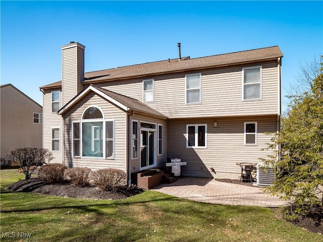 back of property featuring a patio, a lawn, a chimney, and entry steps