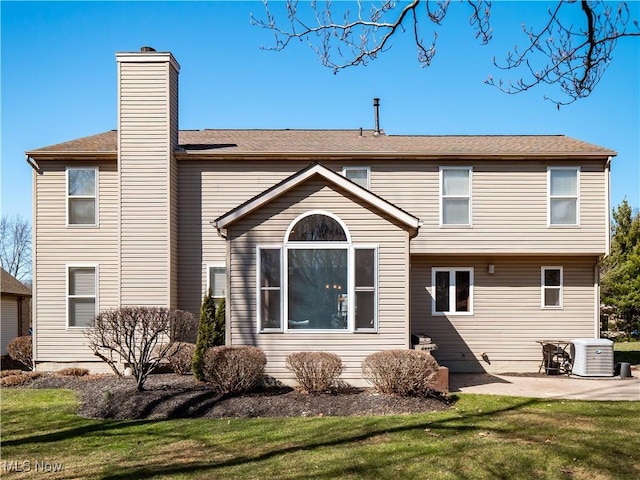 rear view of property featuring a patio area, cooling unit, a chimney, and a yard