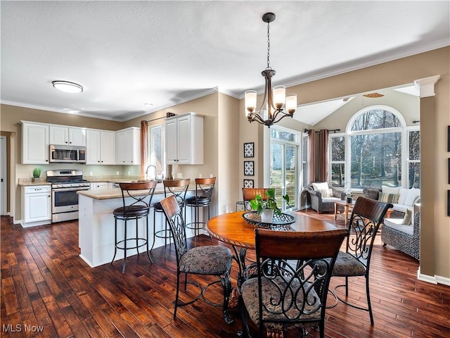 dining area with a notable chandelier, dark wood finished floors, vaulted ceiling, and ornamental molding