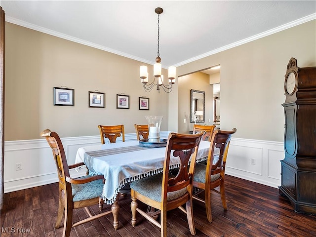 dining room featuring a notable chandelier, wainscoting, dark wood-style flooring, and crown molding