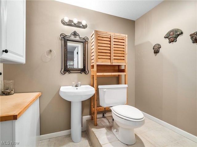 half bath featuring a sink, baseboards, and toilet