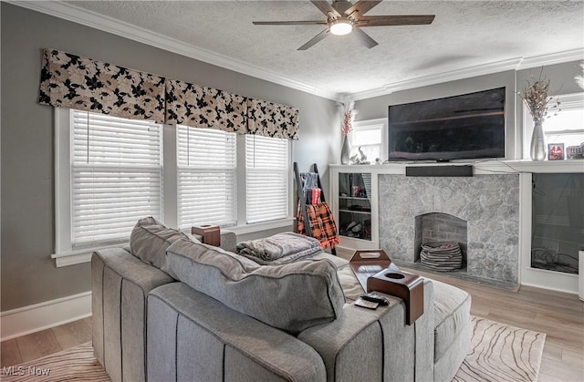 living area with a textured ceiling, a ceiling fan, light wood-style floors, and ornamental molding