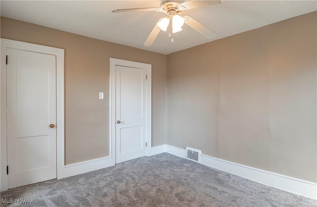 unfurnished room featuring baseboards, carpet, visible vents, and ceiling fan