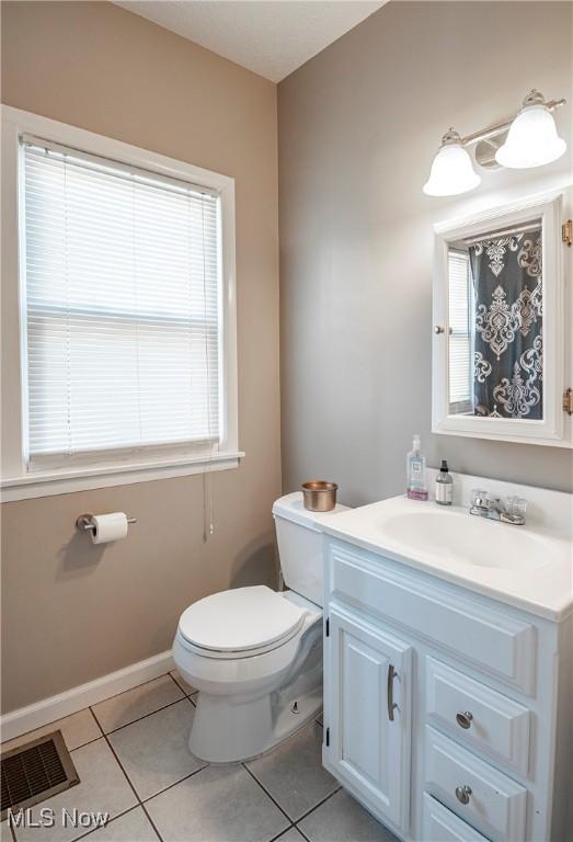 bathroom with vanity, baseboards, visible vents, tile patterned floors, and toilet