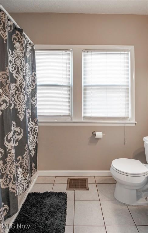 full bath featuring tile patterned floors, toilet, baseboards, and plenty of natural light