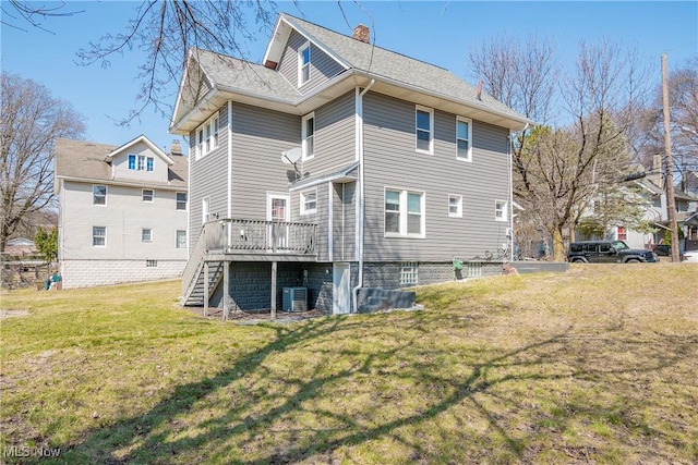 rear view of house featuring a lawn, a chimney, a wooden deck, central AC unit, and stairs