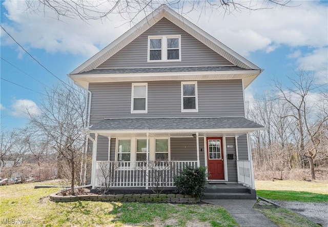 traditional style home featuring a porch, a shingled roof, and a front yard