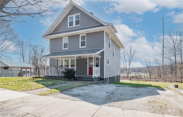 traditional style home with covered porch, a front lawn, and roof with shingles