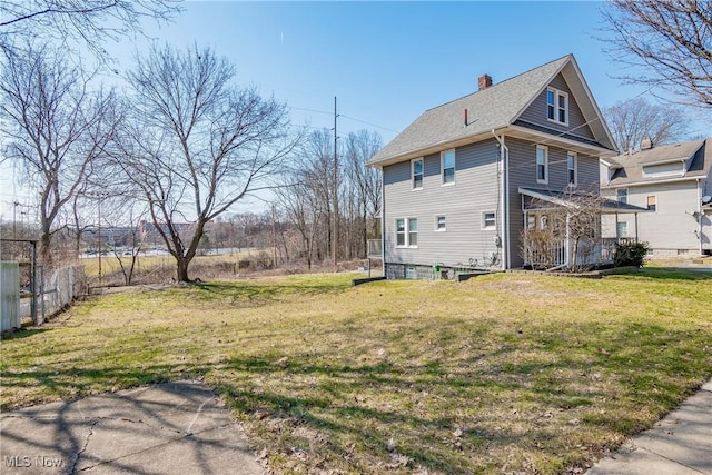 view of property exterior featuring a yard, a shingled roof, a chimney, and fence