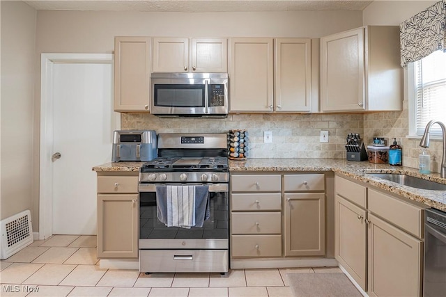 kitchen with light tile patterned floors, visible vents, a sink, decorative backsplash, and stainless steel appliances