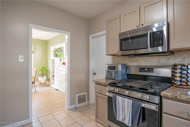 kitchen featuring visible vents, light stone counters, tasteful backsplash, appliances with stainless steel finishes, and light tile patterned floors