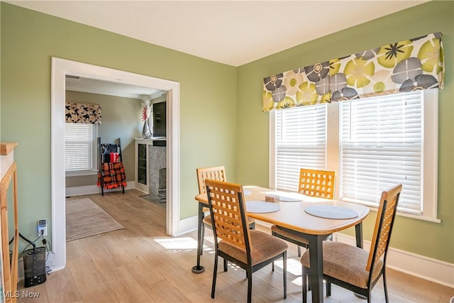 dining area featuring baseboards, light wood-style floors, and a tile fireplace