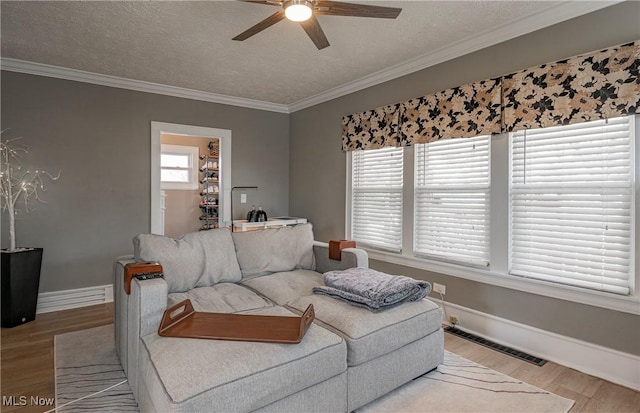 living room featuring visible vents, plenty of natural light, light wood-type flooring, and ornamental molding