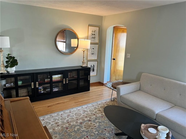 living room with baseboards, arched walkways, a textured ceiling, and wood finished floors