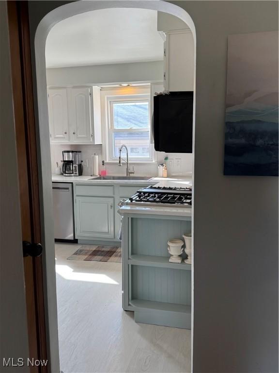 kitchen with light floors, light countertops, stainless steel dishwasher, white cabinets, and a sink