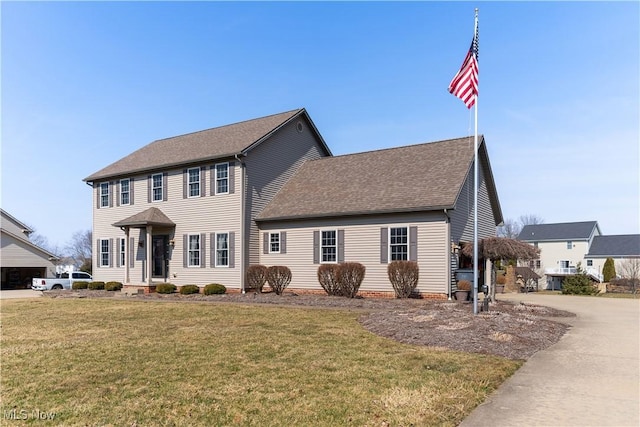 colonial house with a front lawn and a shingled roof