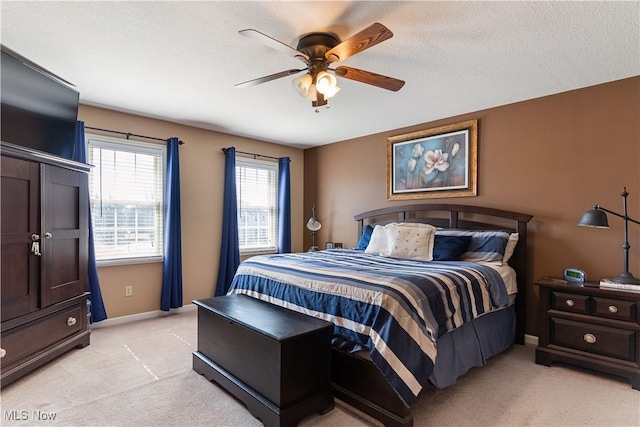 bedroom with light colored carpet, a textured ceiling, baseboards, and ceiling fan