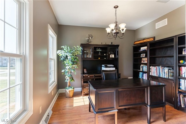 office with light wood finished floors, a notable chandelier, plenty of natural light, and visible vents