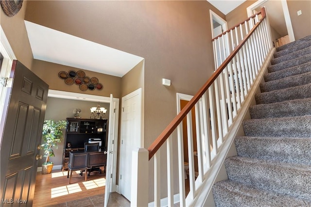 stairway with a chandelier and tile patterned flooring