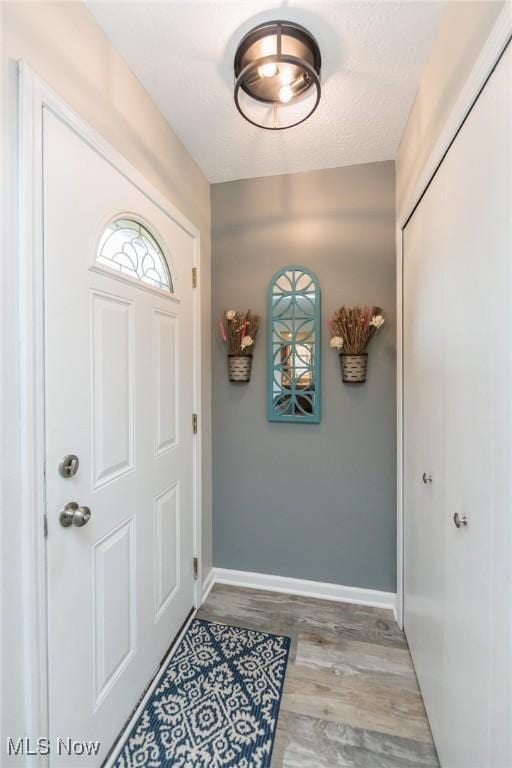 foyer entrance with wood finished floors and baseboards