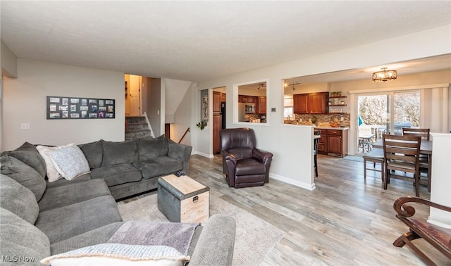 living room featuring baseboards, stairs, and light wood finished floors