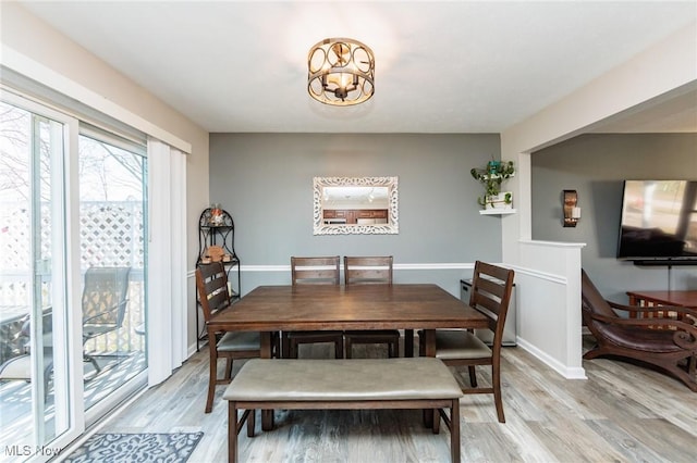 dining area with a chandelier, baseboards, and light wood-style floors