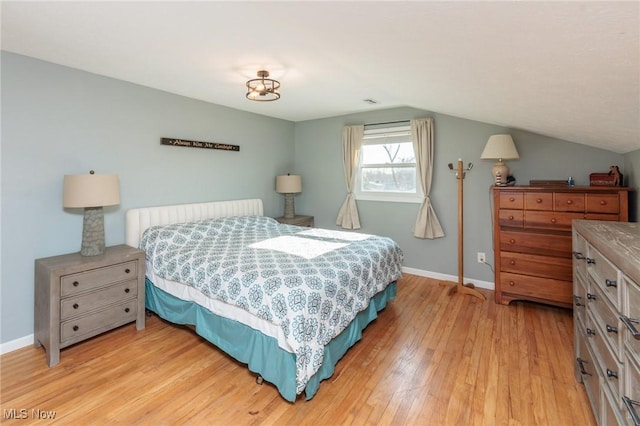 bedroom featuring light wood-type flooring, baseboards, and vaulted ceiling