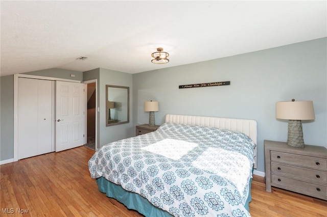 bedroom featuring a closet, baseboards, visible vents, and wood finished floors