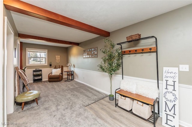 living area with beam ceiling, carpet, and baseboards